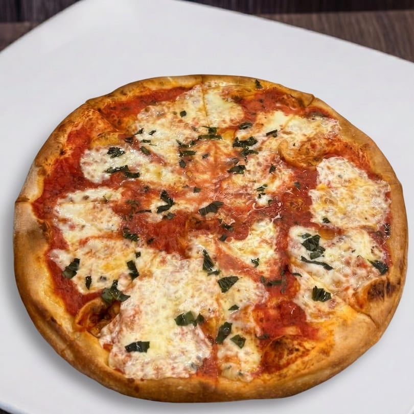 Round Margherita pizza with melted mozzarella, red sauce, and fresh basil on a white plate.